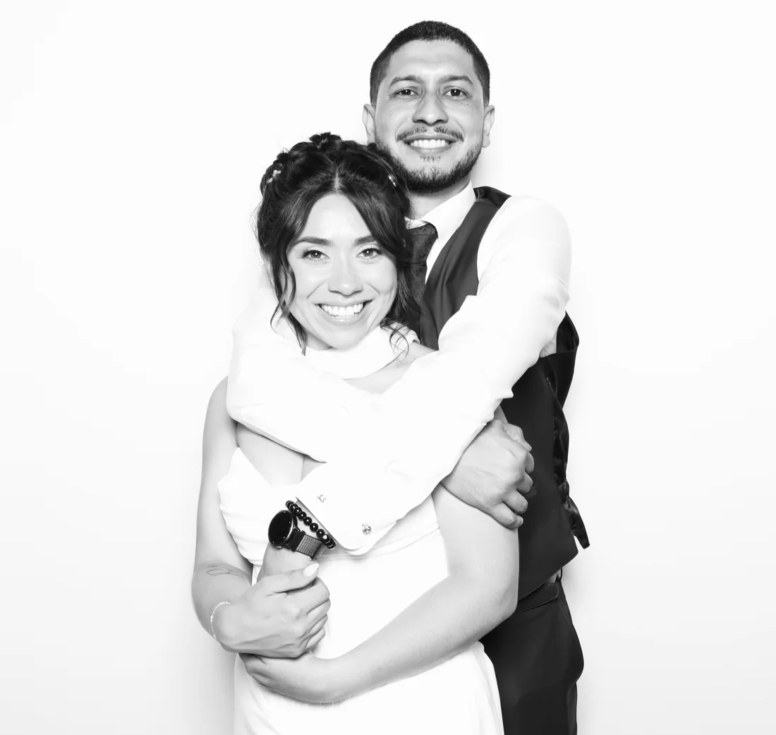 A couple holding each other and laughing in a black and white booth photo