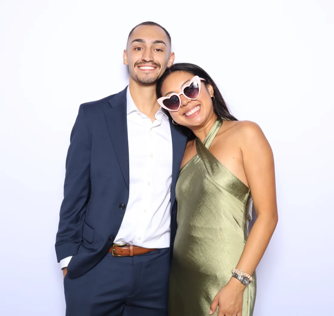 Two guests laughing together, one wearing heart shaped glasses, at the photo booth