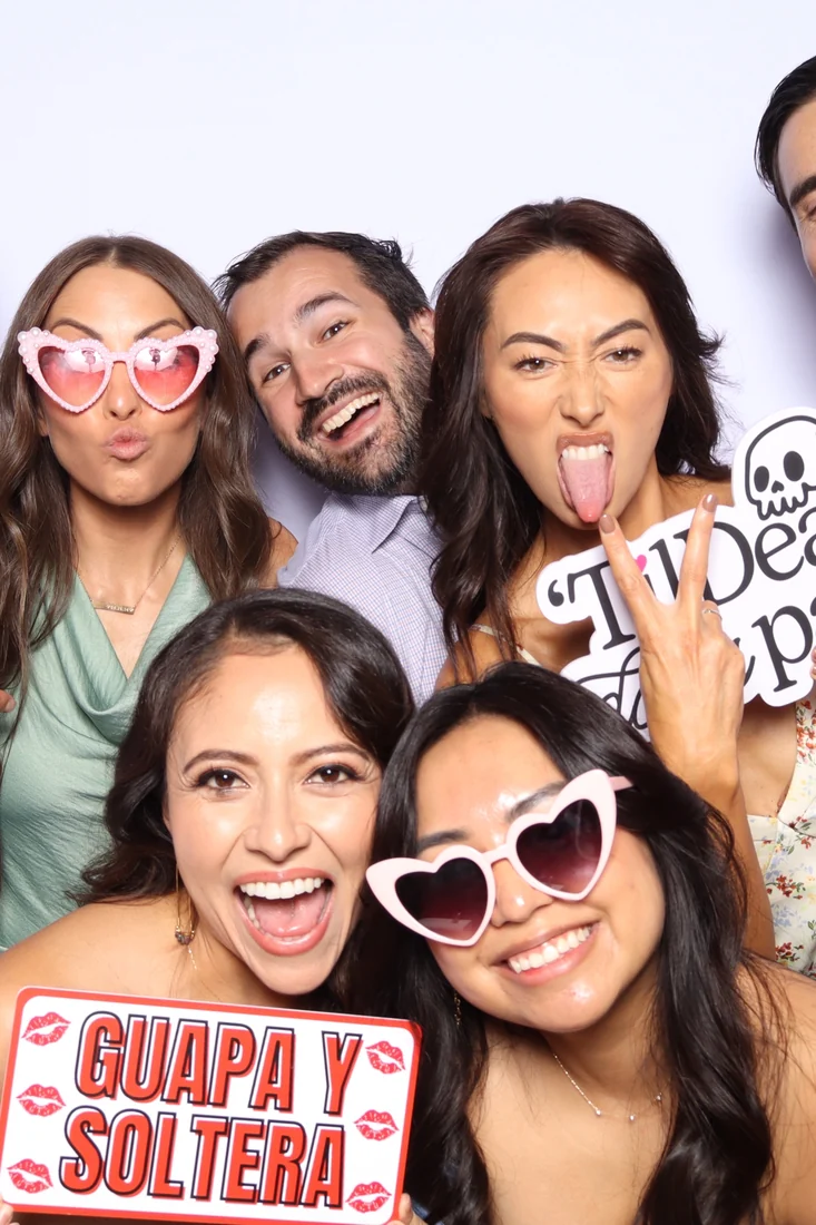 Guests crowding into the booth with signs and props at a private celebration