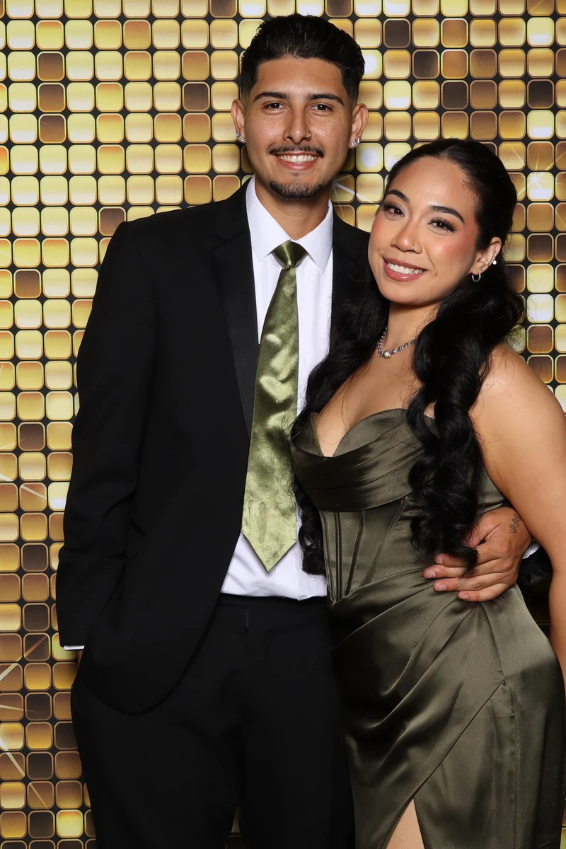 Two guests posing in front of a gold sequin backdrop at a Los Angeles photo booth
