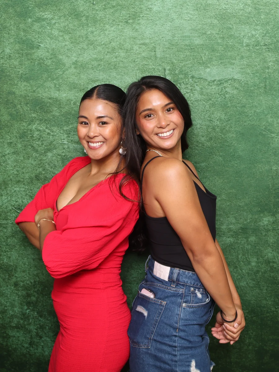 Two guests posing in front of a studio backdrop at a photo booth