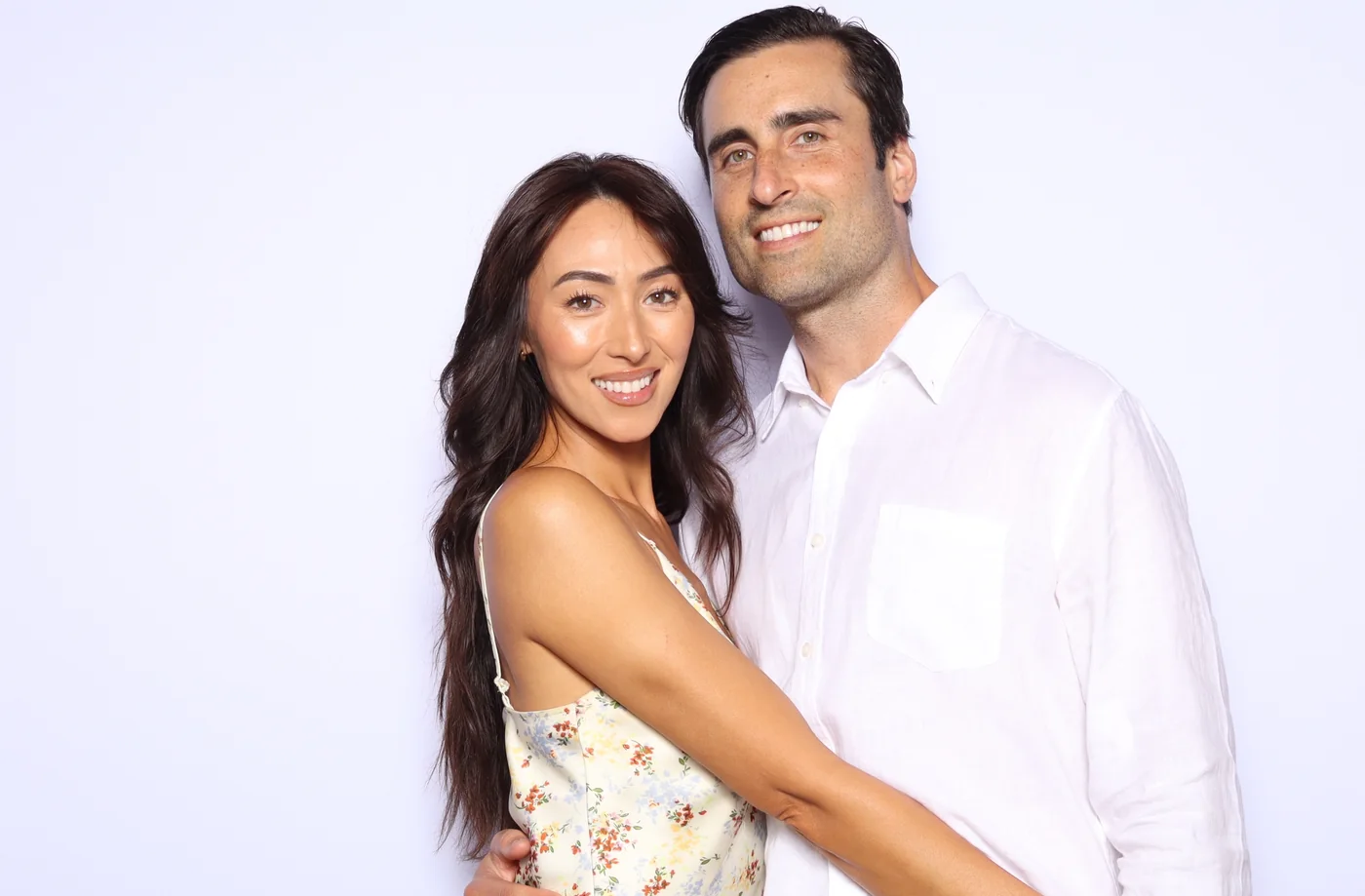 A couple with their arms around each other at the photo booth