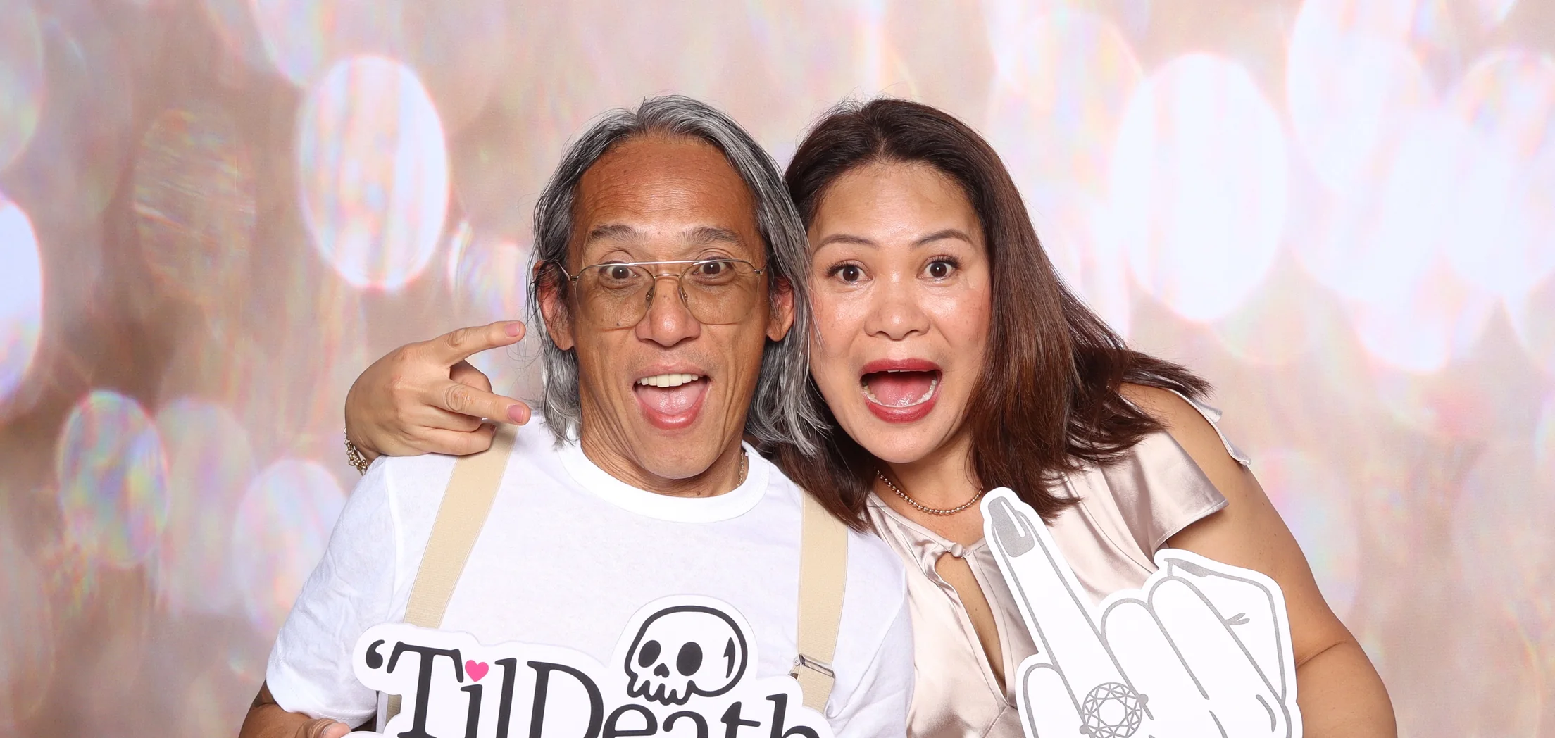 Two guests laughing with props at an Ageless Moments LA photo booth